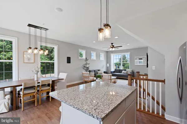 a view of a dining room and livingroom with furniture wooden floor a rug a fireplace and a chandelier