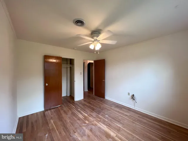 an empty room with closet and a ceiling fan