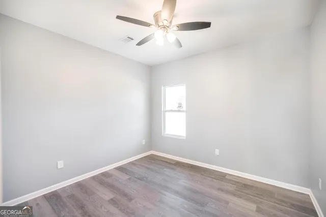 an empty room with windows and fan