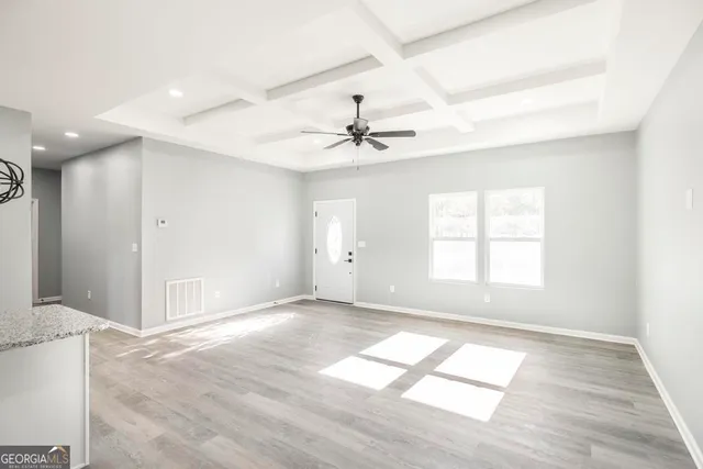 an empty room with chandelier fan and windows