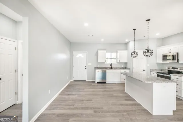 a large white kitchen with cabinets a sink and appliances