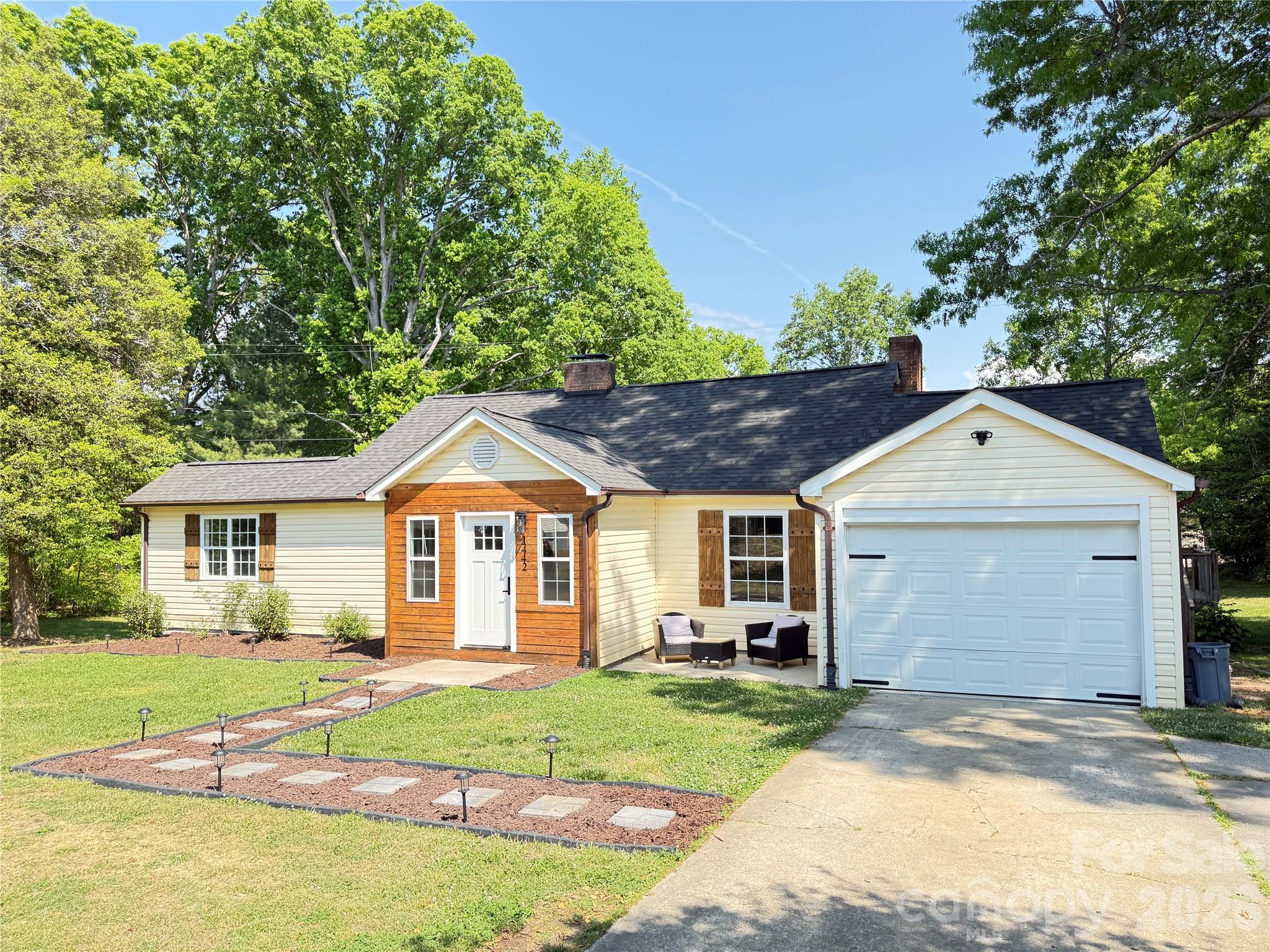 a front view of a house with a garden and trees