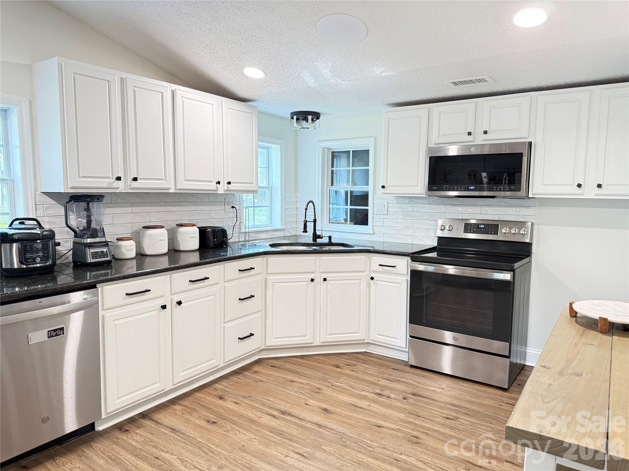 1442 Lee Pearson Road Granite Falls, NC 28630 - Photo 12 of 40 a kitchen with granite countertop white cabinets white stainless steel appliances and sink