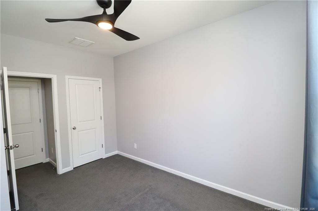 689 Wickham Ridge Road Apex, NC 27539 - Photo 32 of 37 an empty room with a ceiling fan and carpet