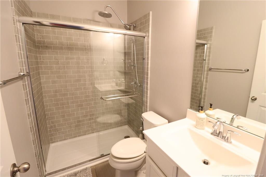 689 Wickham Ridge Road Apex, NC 27539 - Photo 34 of 37 a bathroom with a sink mirror toilet and shower