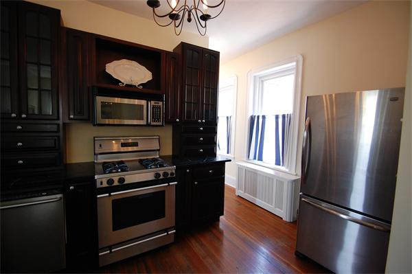 145 Charles Street, Unit 4 Boston, MA 02114 - Photo 8 of 14 a kitchen with wooden floors and stainless steel appliances