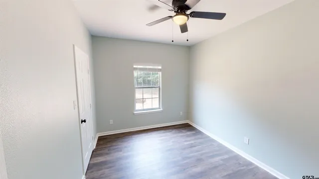an empty room with a window and a fan
