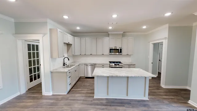 a large kitchen with stainless steel appliances granite countertop a lot of counter space and wooden floors