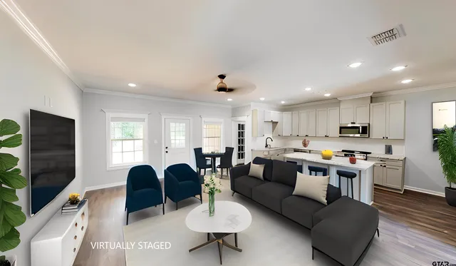 a living room with furniture kitchen view and a flat screen tv
