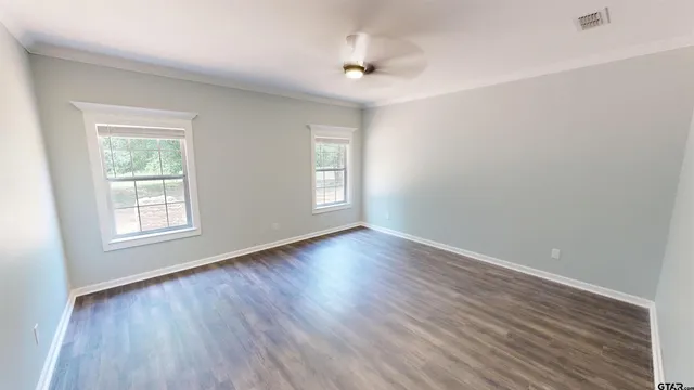 an empty room with wooden floor and windows