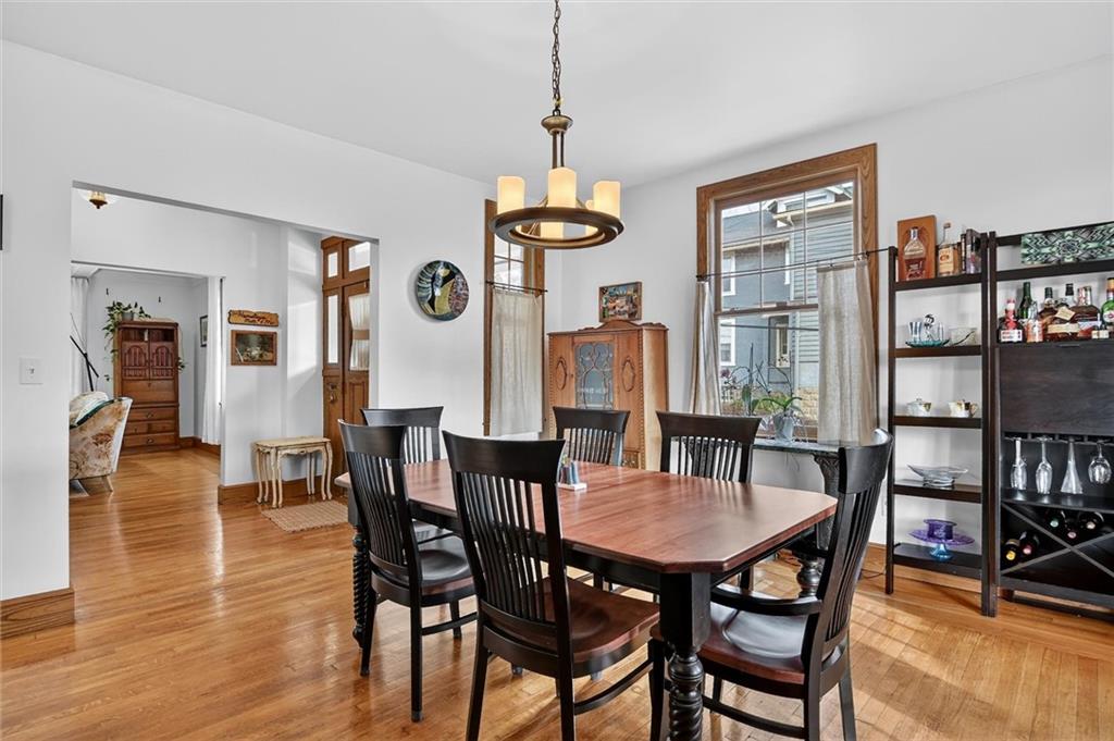 198 Dewey Street Pittsburgh, PA 15218 - Photo 15 of 45 a dining room with wooden floor a chandelier a wooden table and chairs