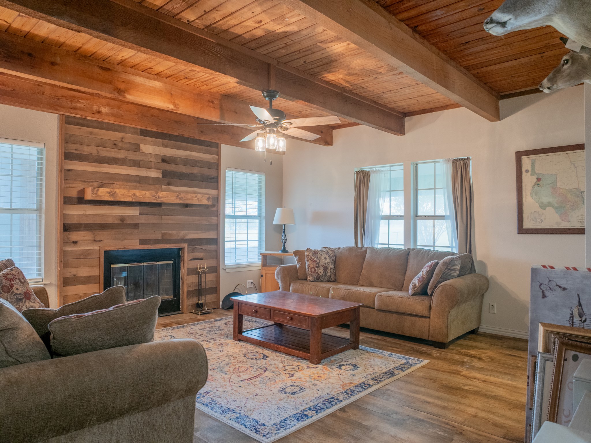 11079 Cr 266 Rochelle Tx 76872 Rochelle, TX 76872 - Photo 12 of 40 Living space featuring a wood-plank accent wall with a built-in fireplace, a wood-finish vaulted ceiling with exposed beams, and multiple windows