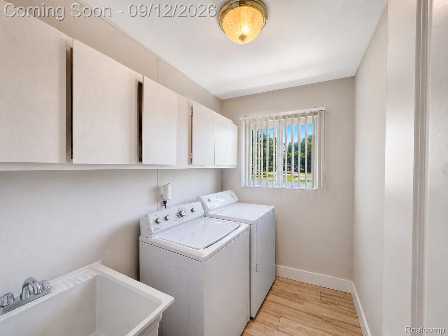 34398 Greentrees Road Sterling Heights, MI 48312 - Photo 21 of 36 Laundry room featuring overhead white cabinetry, a utility sink with dual-handle faucet, and wood-finish flooring