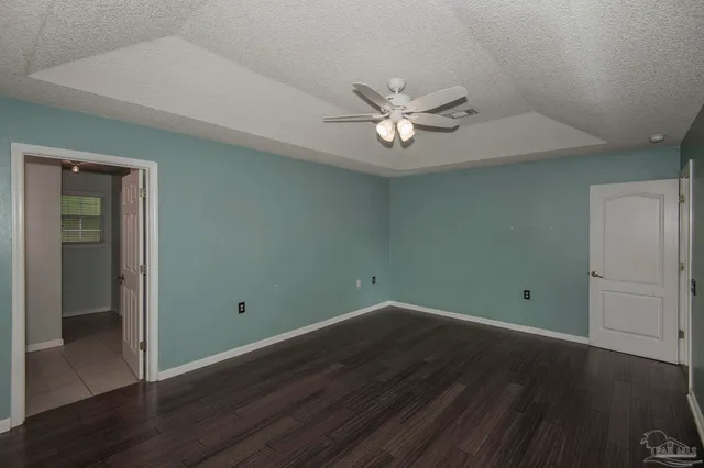 an empty room with wooden floor and ceiling fan