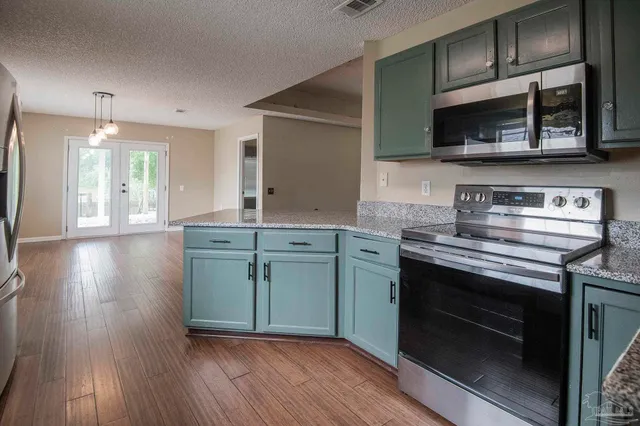 a kitchen with stainless steel appliances granite countertop a stove a sink and a microwave