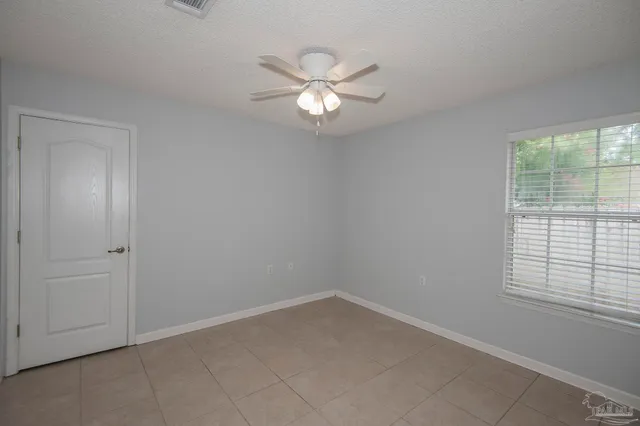 an empty room with windows and fan