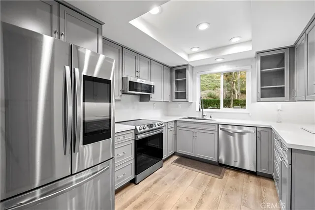 a kitchen with granite countertop stainless steel appliances a sink cabinets and a window