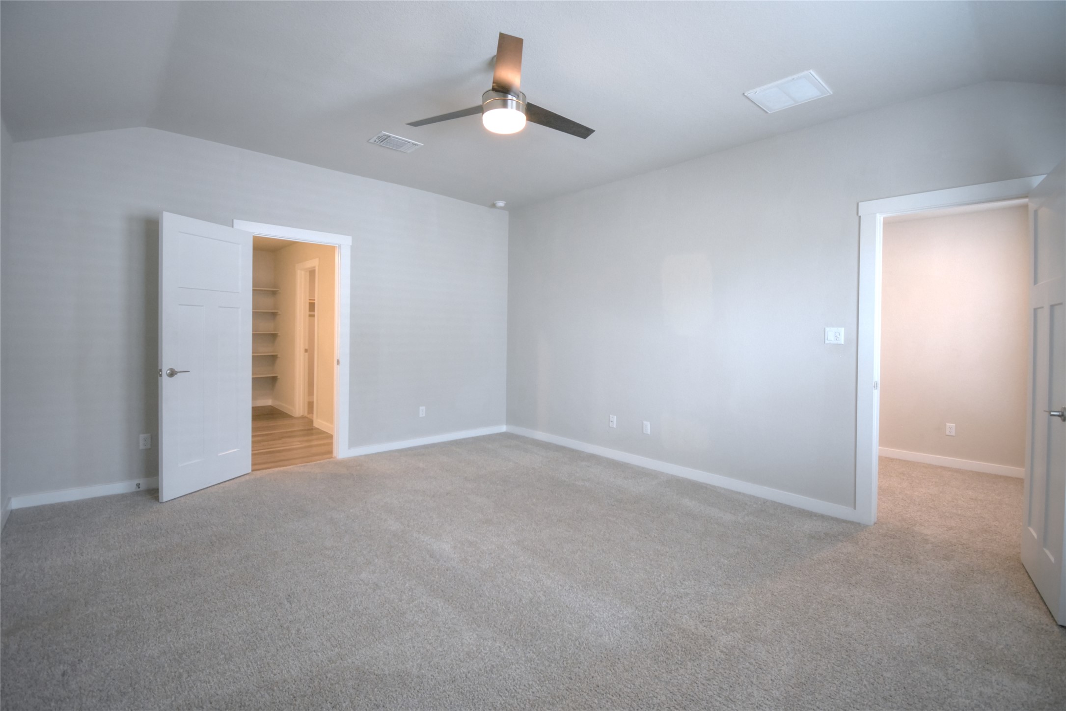 1137 Tipton Street Georgetown, TX 78633 - Photo 6 of 18 Primary bedroom featuring a spacious bathroom, with walk-in closet, light colored carpet, and ceiling fan