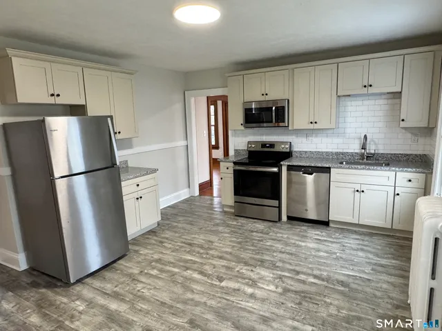 a kitchen with stainless steel appliances granite countertop a refrigerator stove a sink and a microwave