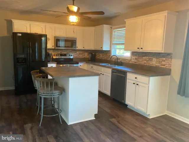 a kitchen with a sink a counter space appliances and cabinets