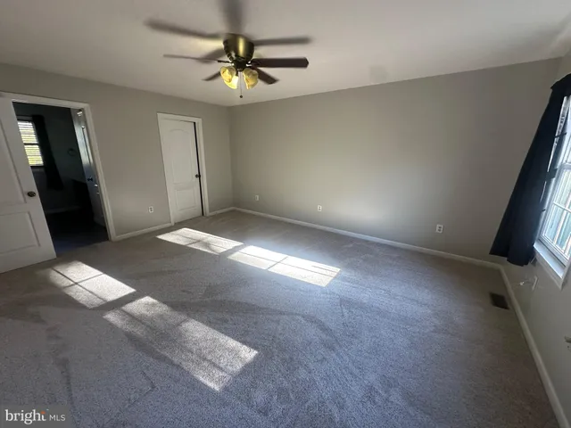 en empty room with closet and a chandelier fan