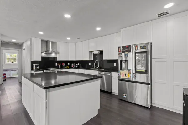 a kitchen with stainless steel appliances granite countertop a stove top oven a sink dishwasher a dining table and chairs with wooden floor