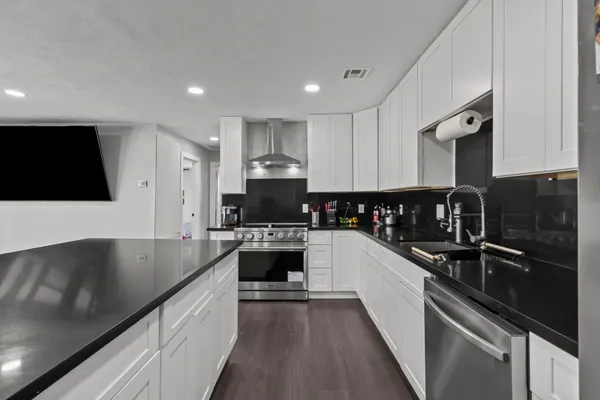 a kitchen with granite countertop a sink stainless steel appliances and white cabinets
