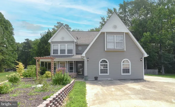 a view of a yard in front of a house with plants and large tree