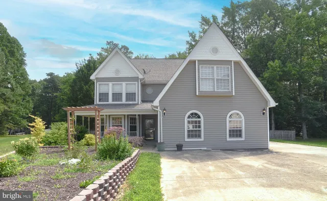 a view of a yard in front of a house with plants and large tree