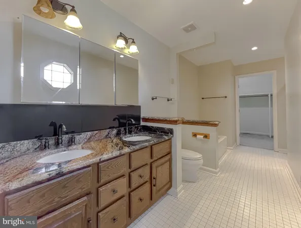 a bathroom with a granite countertop sink a toilet and a mirror