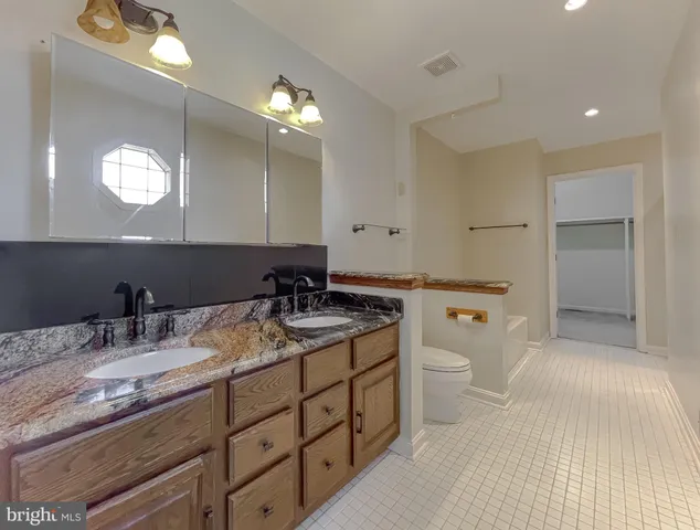 a bathroom with a granite countertop sink a toilet and a mirror