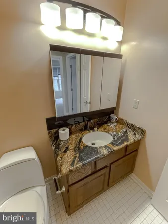a bathroom with a granite countertop sink and a toilet