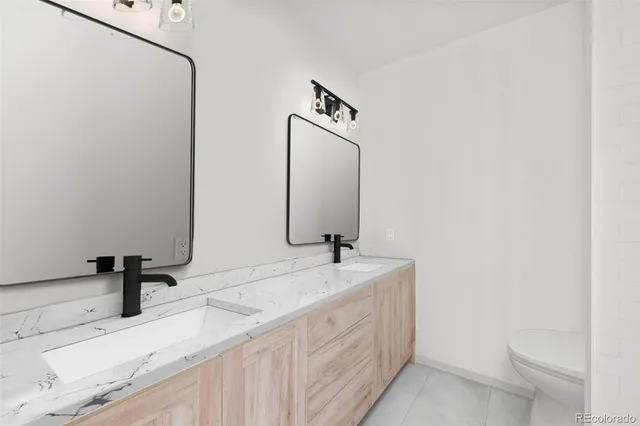 a bathroom with a granite countertop sink a toilet and shower