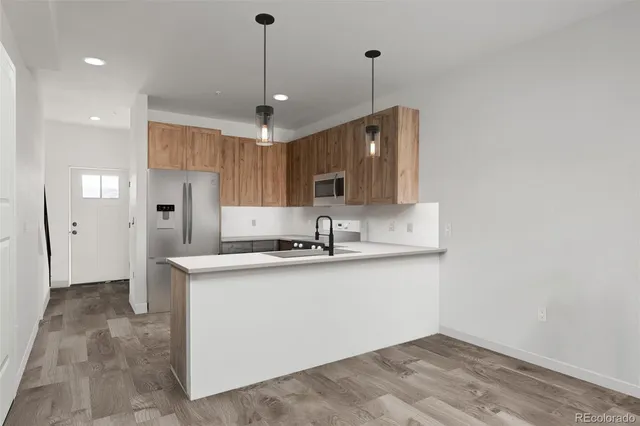 a kitchen with stainless steel appliances granite countertop a sink a stove a refrigerator and island with wooden floor