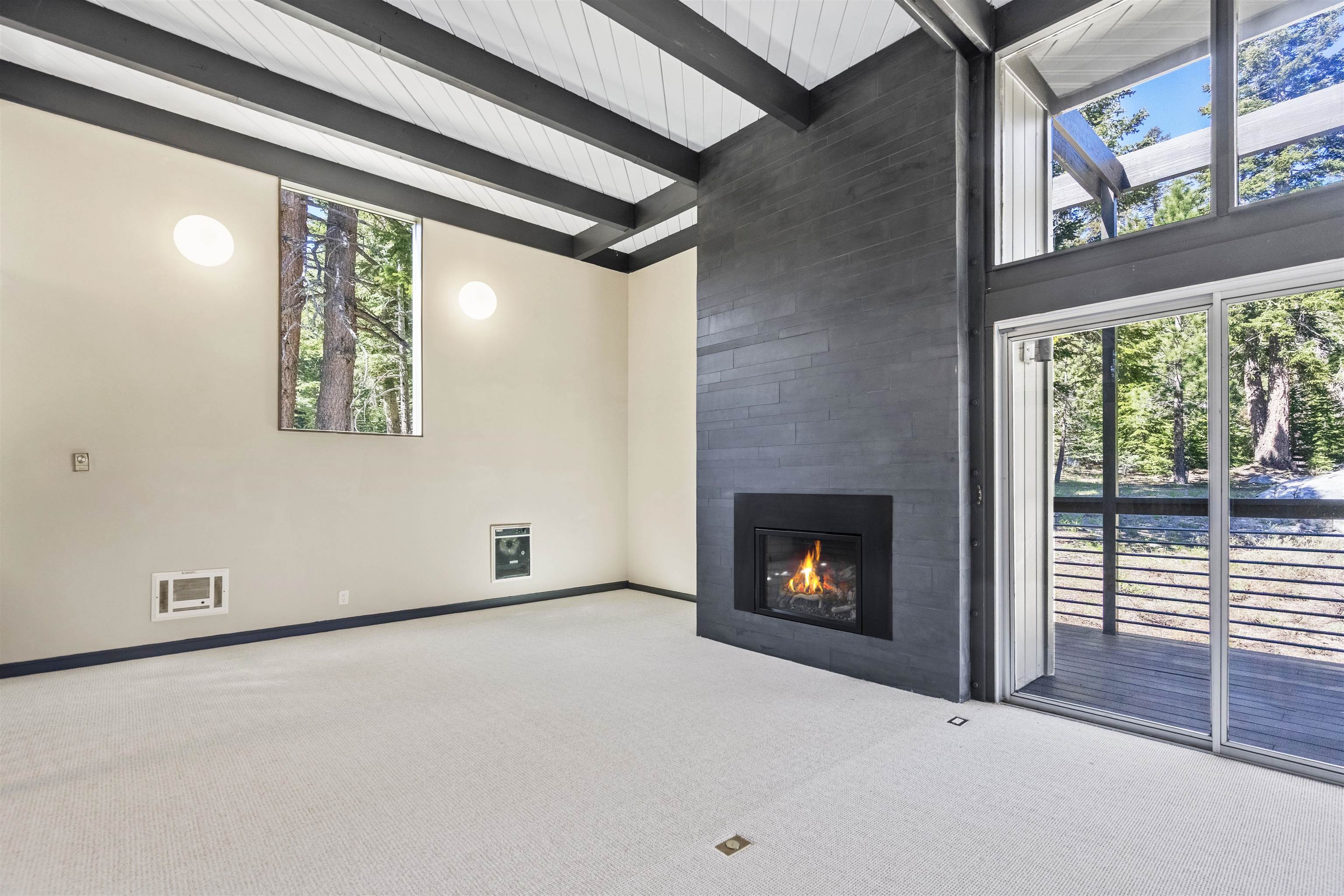 2570 Old Mammoth Road Mammoth Lakes, CA 93546 - Photo 3 of 39 Spacious living area featuring a modern fireplace, exposed beam ceiling, and large sliding glass doors opening to an outdoor deck