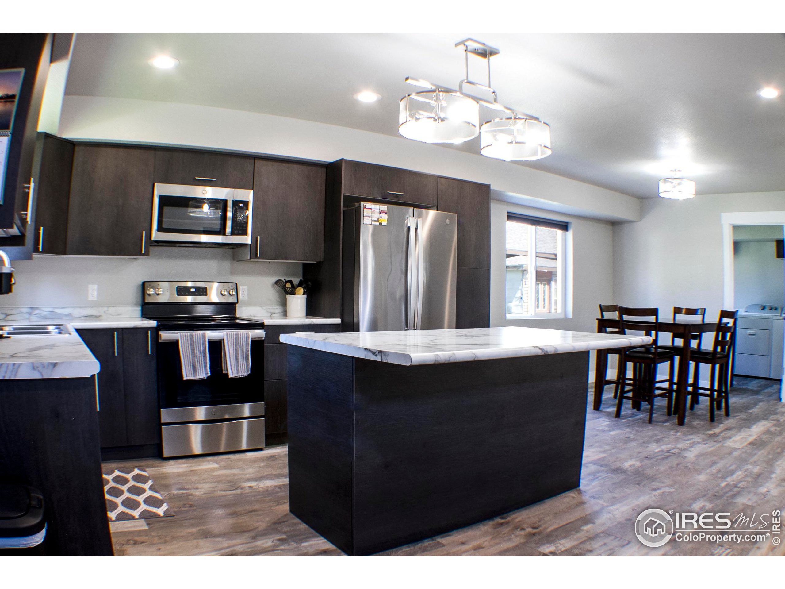 313 West Furry Street Holyoke, CO 80734 - Photo 7 of 23 a kitchen with stainless steel appliances granite countertop a stove a refrigerator a kitchen island a dining table and chairs