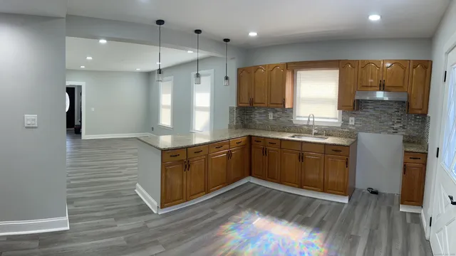 a kitchen with stainless steel appliances granite countertop a sink a stove and a wooden floor