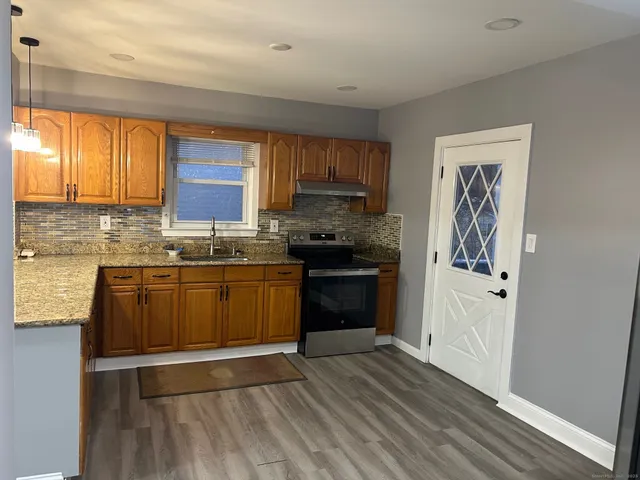 a kitchen with a sink wooden floor and stainless steel appliances
