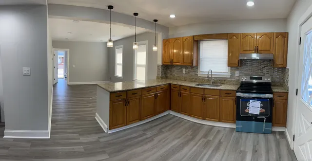 a kitchen with stainless steel appliances granite countertop a sink a stove and a wooden floors