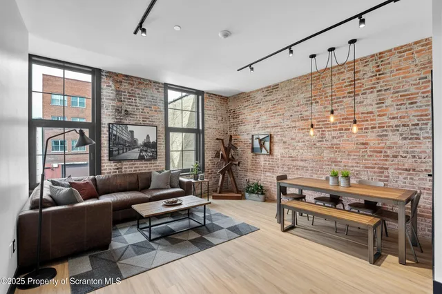 a living room with furniture large windows and wooden floor