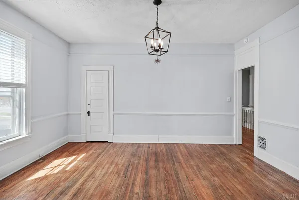 an empty room with wooden floor cabinet and windows