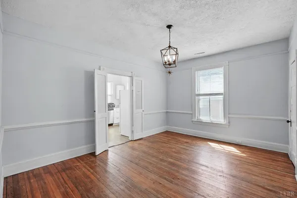 a view of empty room with wooden floor and window