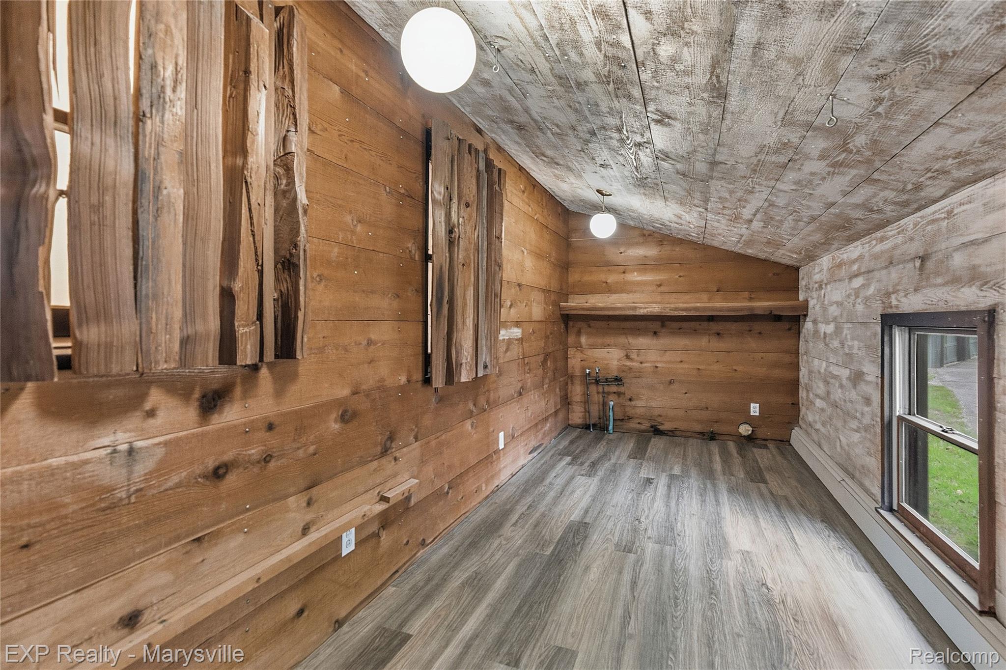 3345 Beach Road Port Huron, MI 48060 - Photo 15 of 89 Empty room featuring lofted ceiling, wood finished floors, and wooden walls