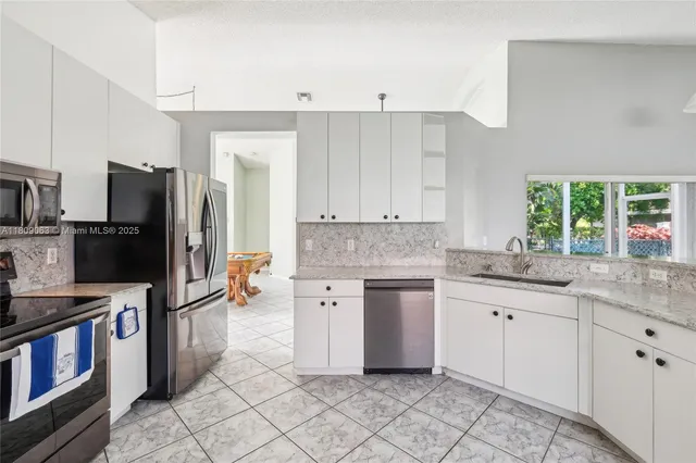a kitchen with granite countertop a refrigerator stove and sink