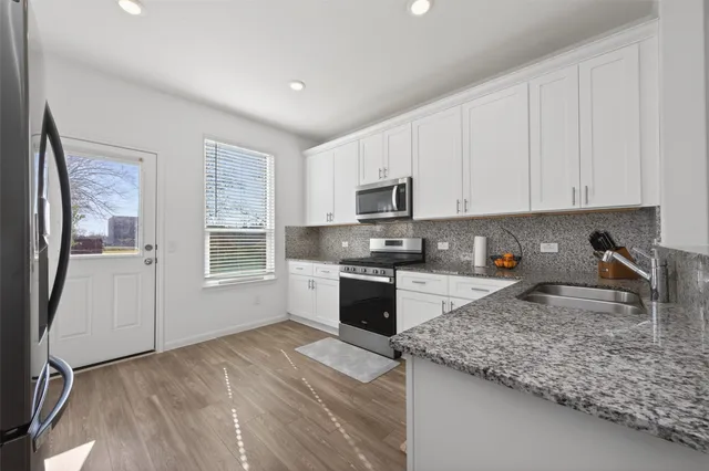 a kitchen with stainless steel appliances granite countertop a table chairs refrigerator sink and cabinets