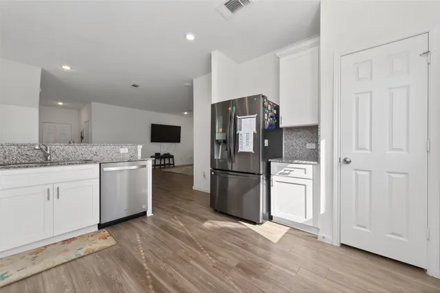 a kitchen with stainless steel appliances wooden floor and a window