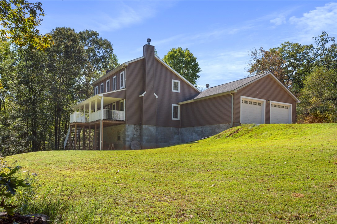 621 Burns Mill Road West Union, SC 29696 - Photo 30 of 45 A spacious home with a wide wrap-around porch and a detached two-car garage set on a verdant hillside.