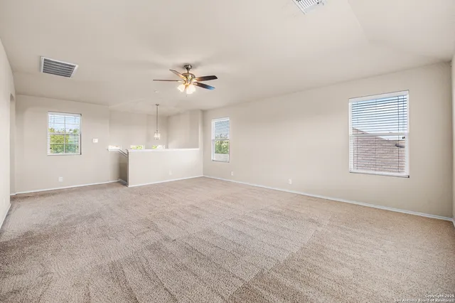 a view of a big room with windows and chandelier fan