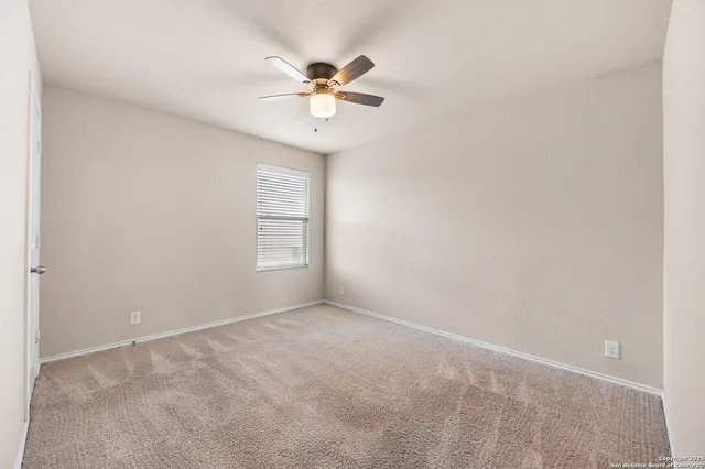 an empty room with a chandelier fan and windows