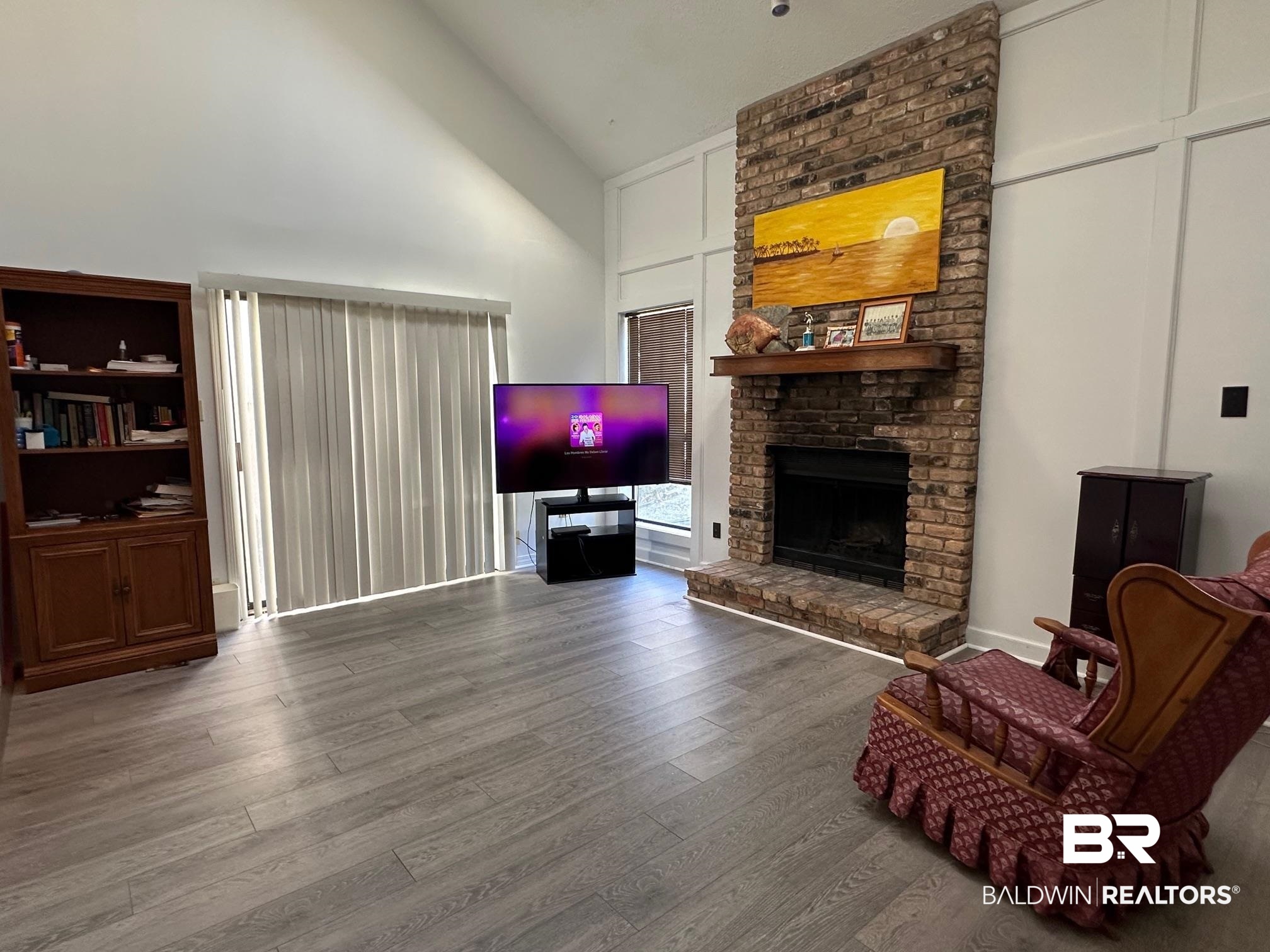 6533 Cedar Bend Court, Unit A Mobile, AL 36608 - Photo 4 of 16 Living area featuring wood finished floors, a brick fireplace, and vaulted ceiling